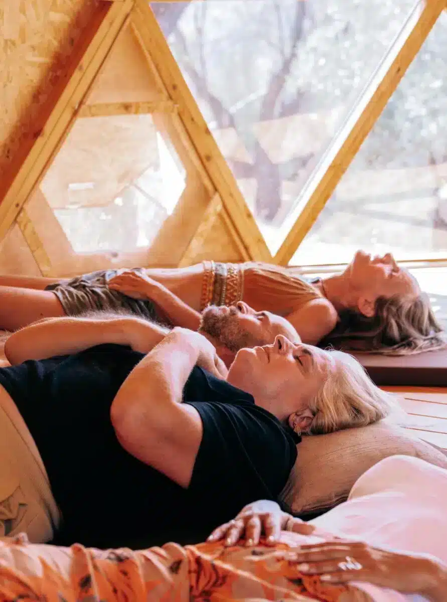 Two guests lying down relaxing inside the geodesic dome bathed in golden light at Costa del Soul retreat