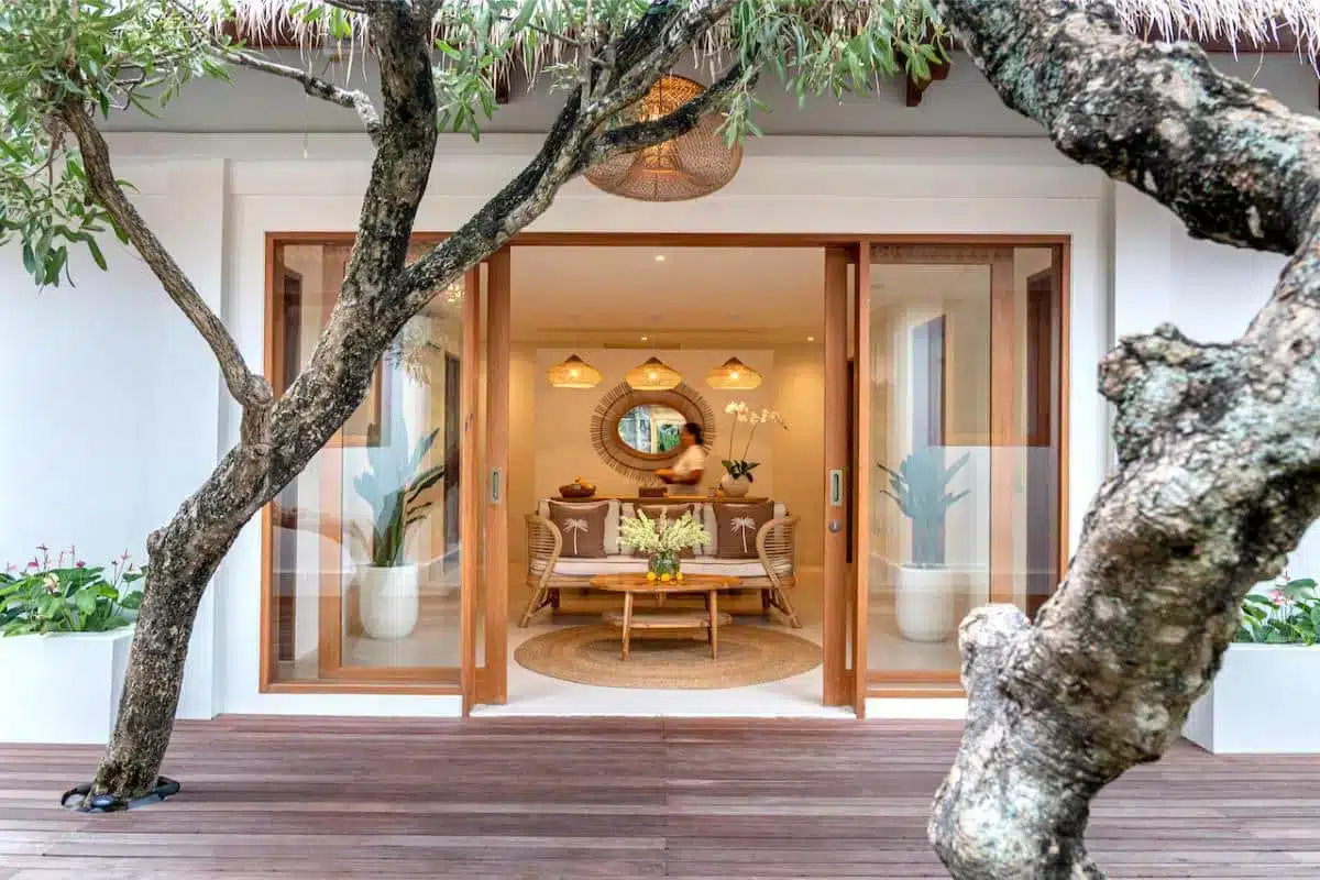Goddess Retreats spa and wellness center exterior with warm interior lighting wooden deck and tropical tree in Ubud Bali