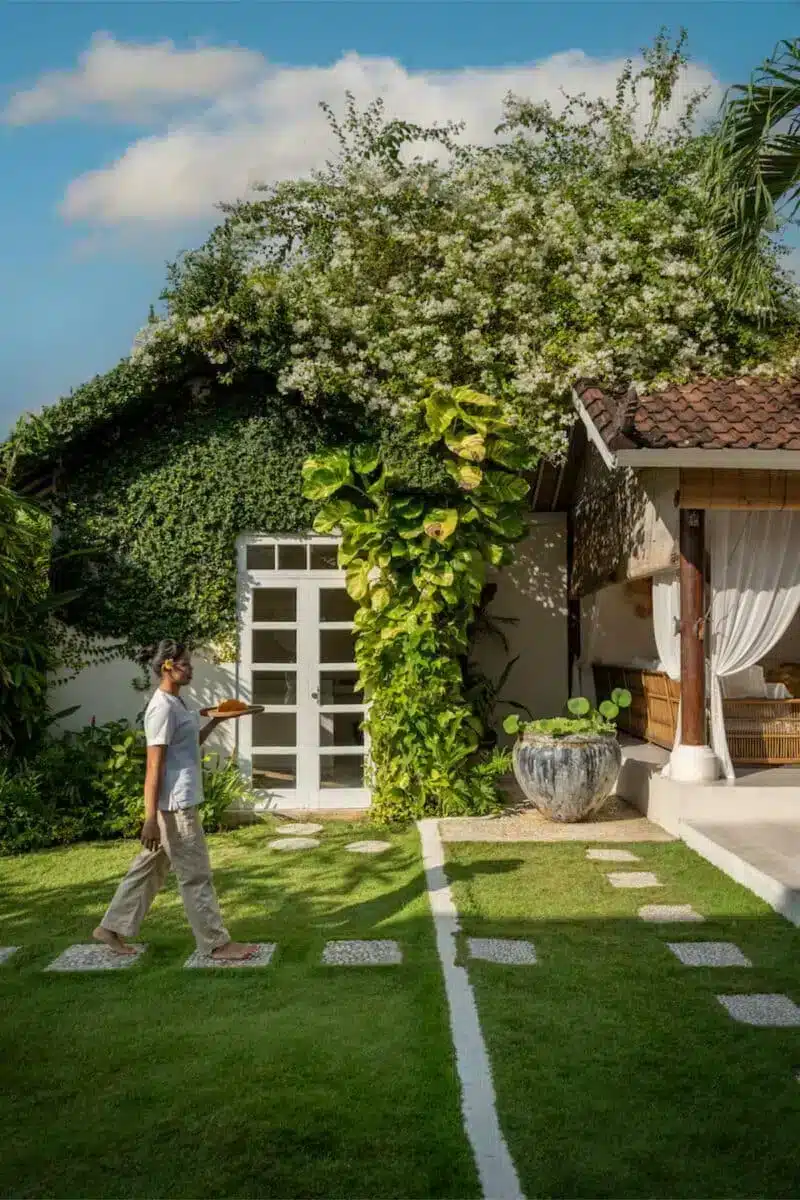 Ivy-covered entrance to the Goddess Retreats villa in Seminyak Bali with stepping stones and tropical garden