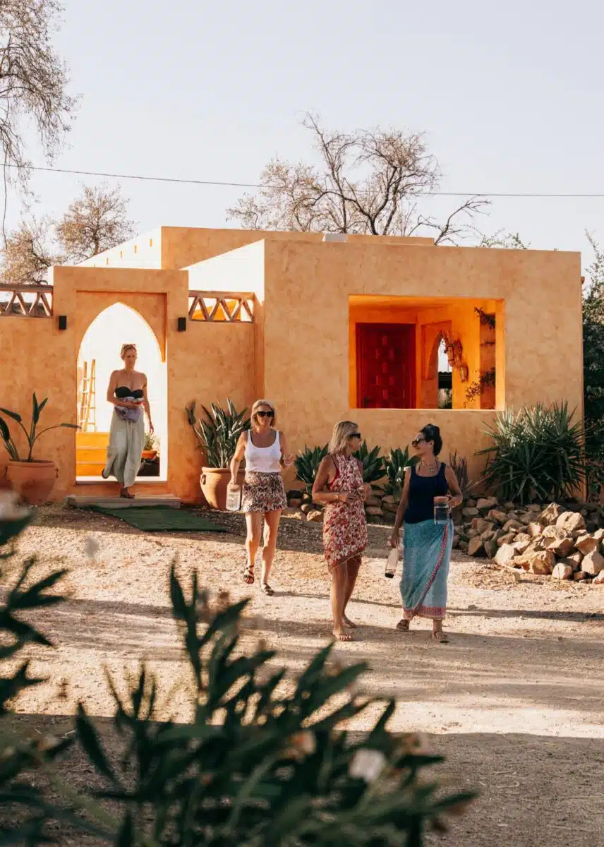Group of women guests walking together outside a terracotta building with Moroccan-style arched entrance at Costa del Soul
