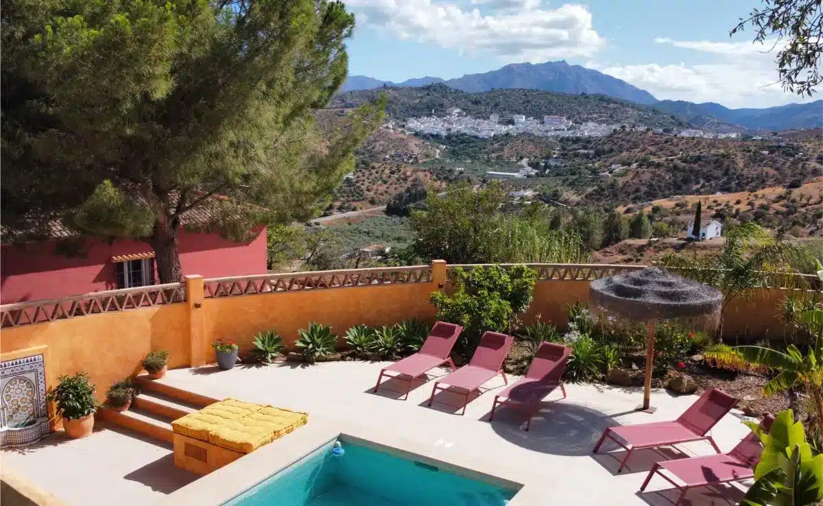 Pool area with sunbeds and terracotta walls offering panoramic views of mountains and white Andalusian village at Costa del Soul