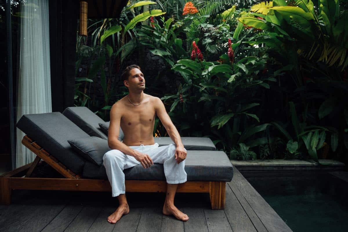 Guest sitting on sunbed beside the private plunge pool on the wooden terrace at Desa Hay Bali