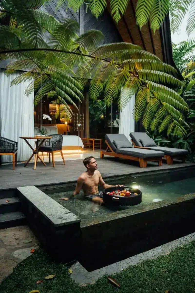Guest enjoying the private plunge pool at night with floating candle tray and warm ambient villa lighting at Desa Hay Bali