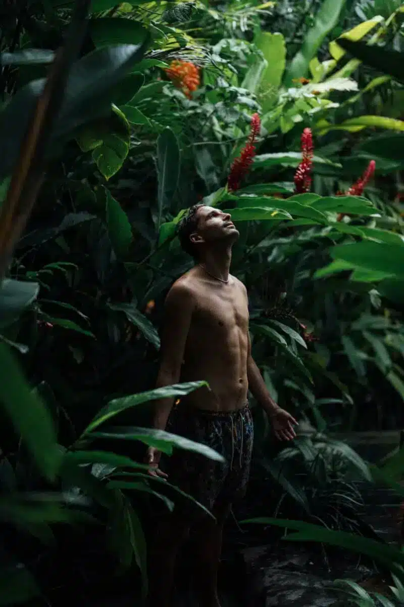 Guest standing among lush tropical plants in the private garden at Desa Hay Bali looking up at the canopy