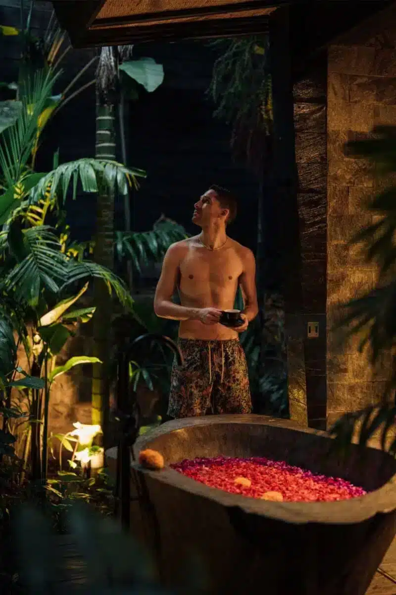 Guest standing among tropical plants near the villa entrance at dusk at Desa Hay Bali