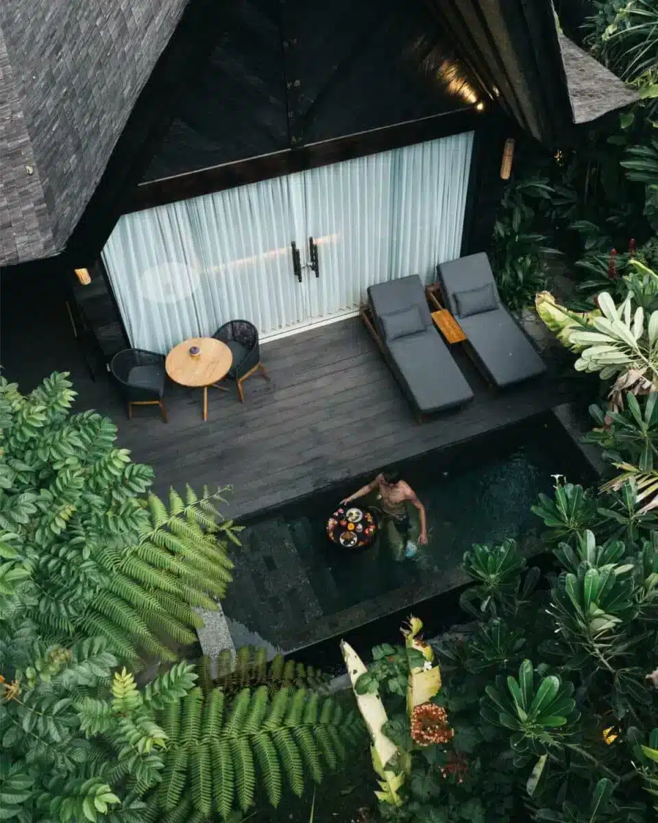 Aerial view of the villa terrace with sunbeds and plunge pool showing the dark pitched roof and tropical garden at Desa Hay Bali