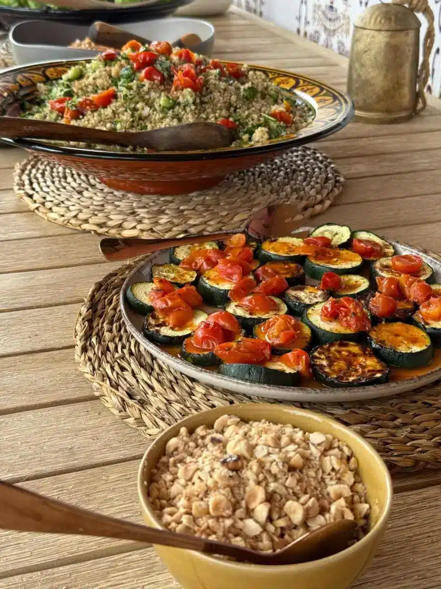 Spread of healthy Mediterranean dishes including roasted vegetables stuffed tomatoes and oats on a wooden table at Costa del Soul