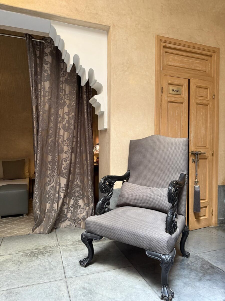 Eleganter gepolsterter Sessel mit drapiertem Vorhang im marokkanisch gestalteten Interieur des Les Bains D’Orient Hammam Marrakesch