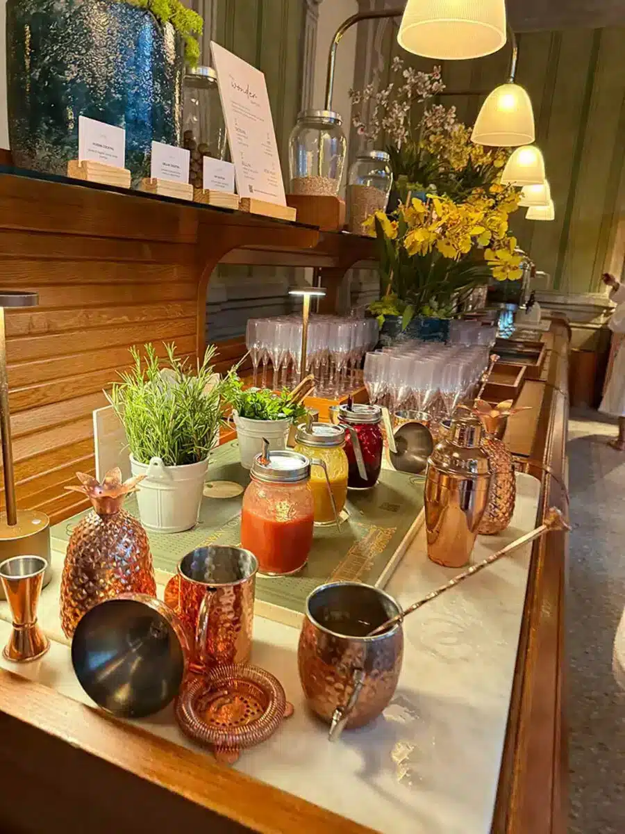 Buffet-Getränkestation mit kupfernen Cocktailshakern frischen Säften und Kräutergarnituren im QC Terme Milano