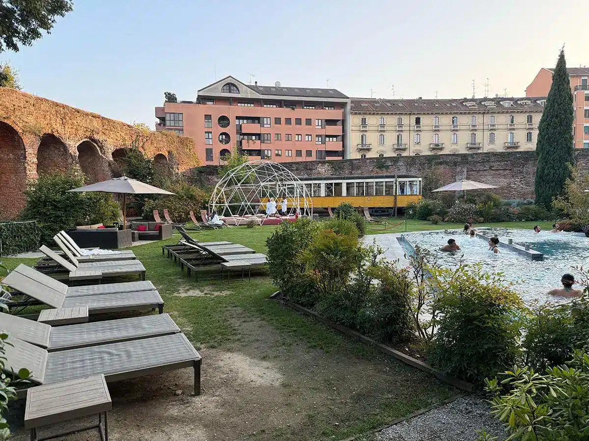 Außenbereich mit Sonnenliegen antiken Steinmauern und historischen Gebäuden in der Dämmerung im QC Terme Milano