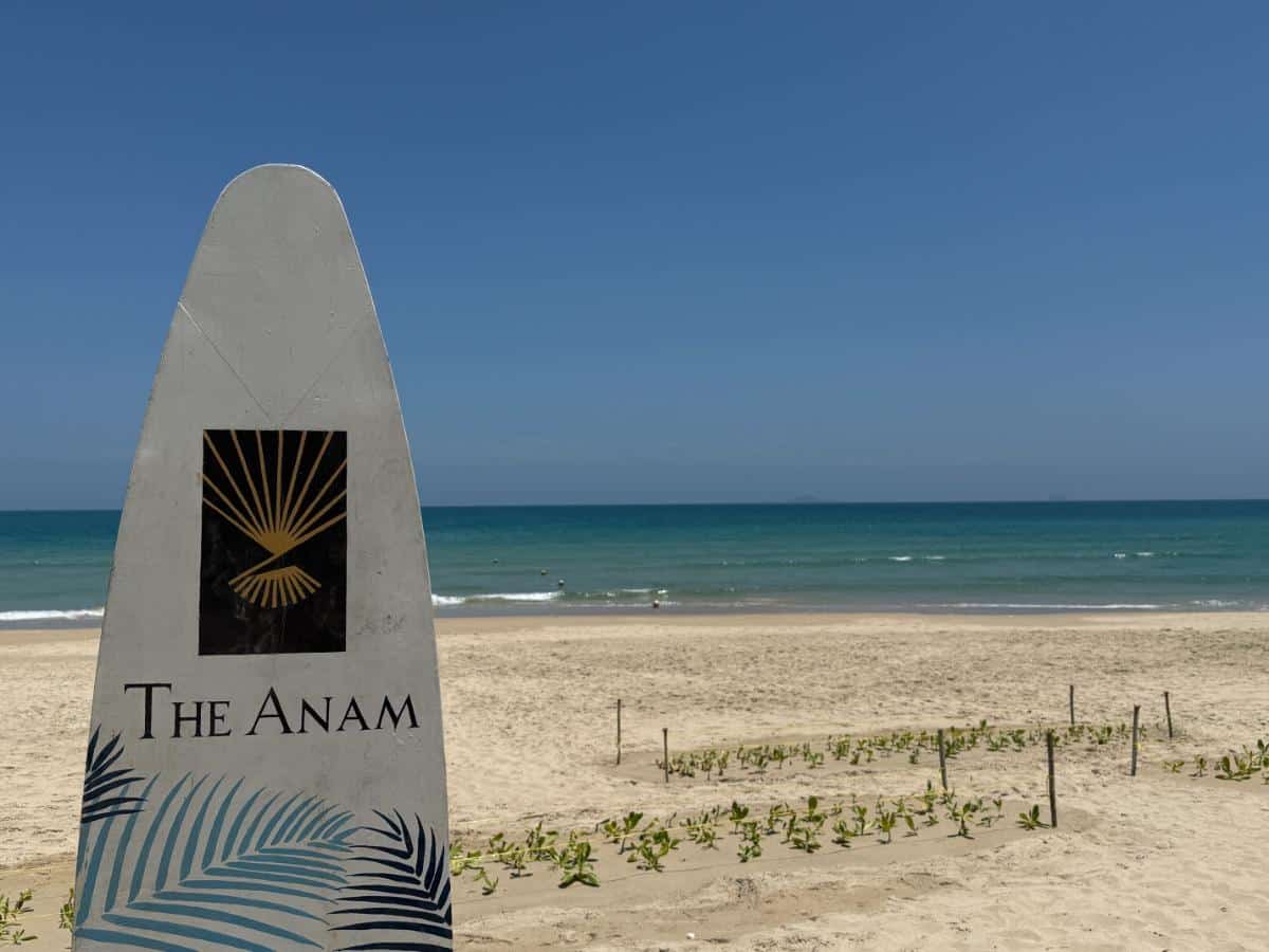 Das Surfbrett der Marke Anam steht am weißen Sandstrand mit Blick auf den Ozean in Cam Ranh