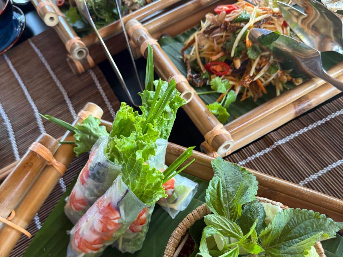 Frische vietnamesische Frühlingsrollen, serviert auf einem Bambustablett mit Salat und Kräutern im The Anam Cam Ranh