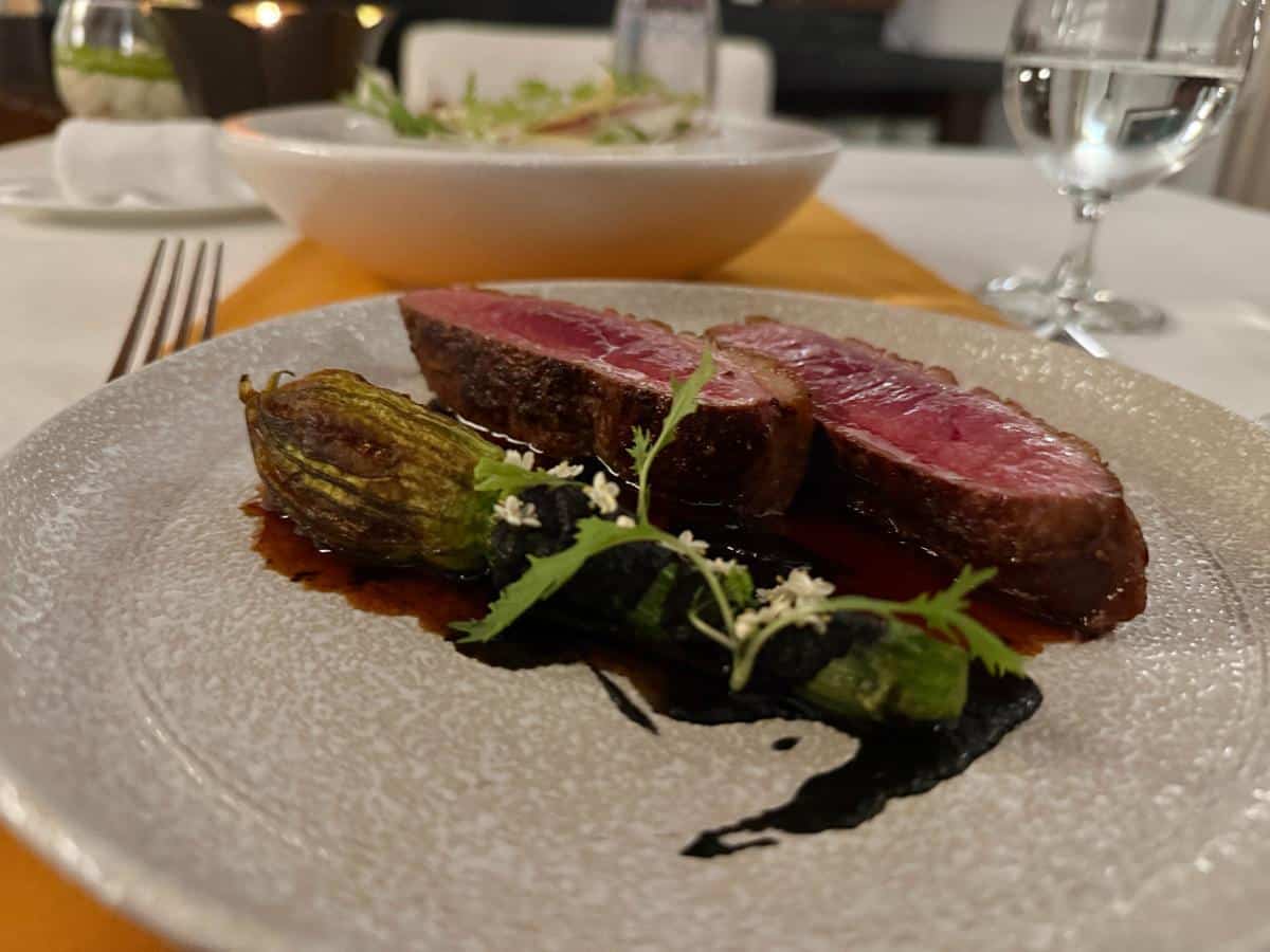 Gebratenes Fleisch mit Grünzeug und kunstvoll angerichteten Tellern im Fine Dining Restaurant des The Anam Cam Ranh