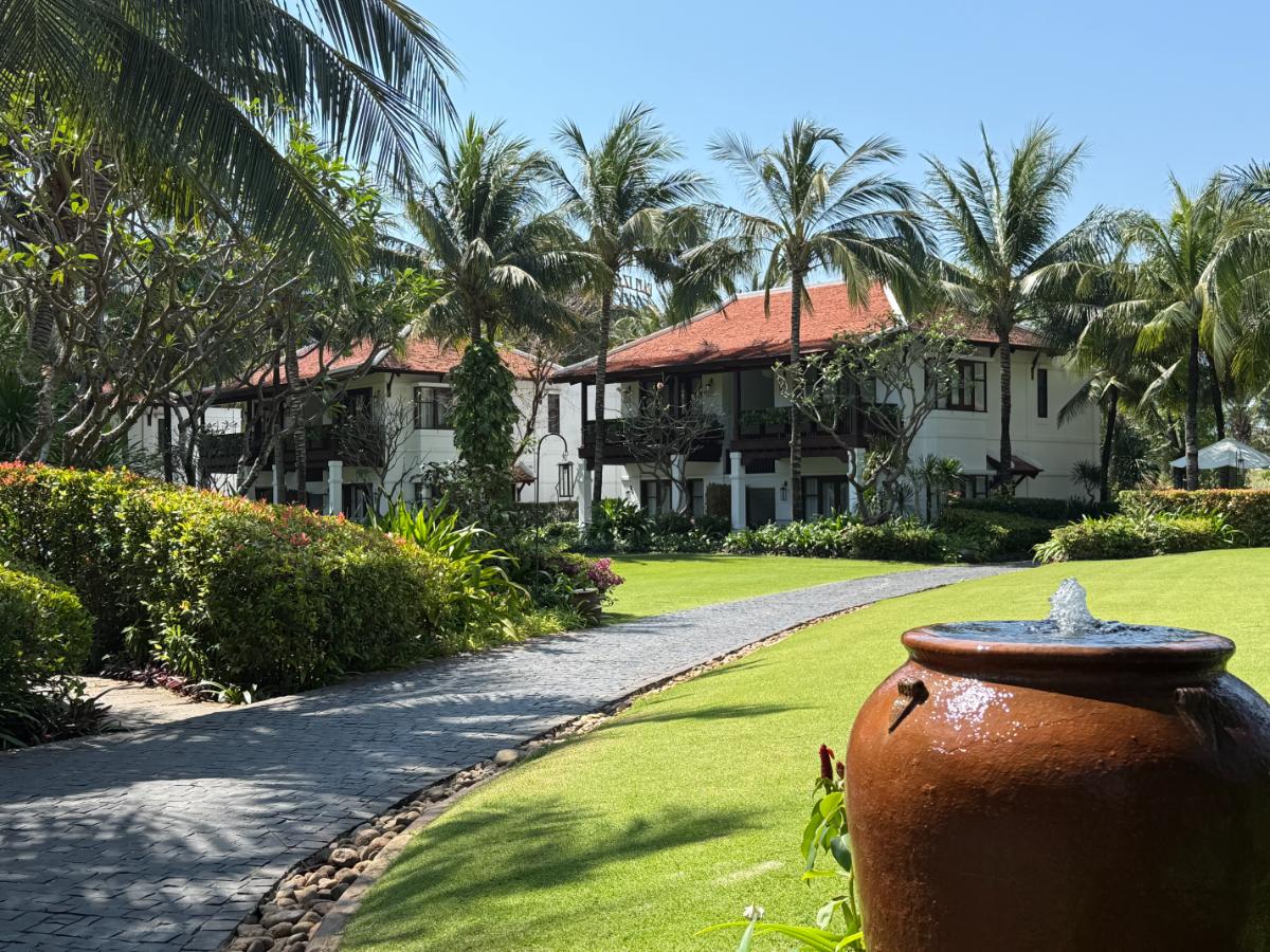 Üppiges Resortgelände im The Anam Cam Ranh mit Brunnen im Kolonialstil und Palmen
