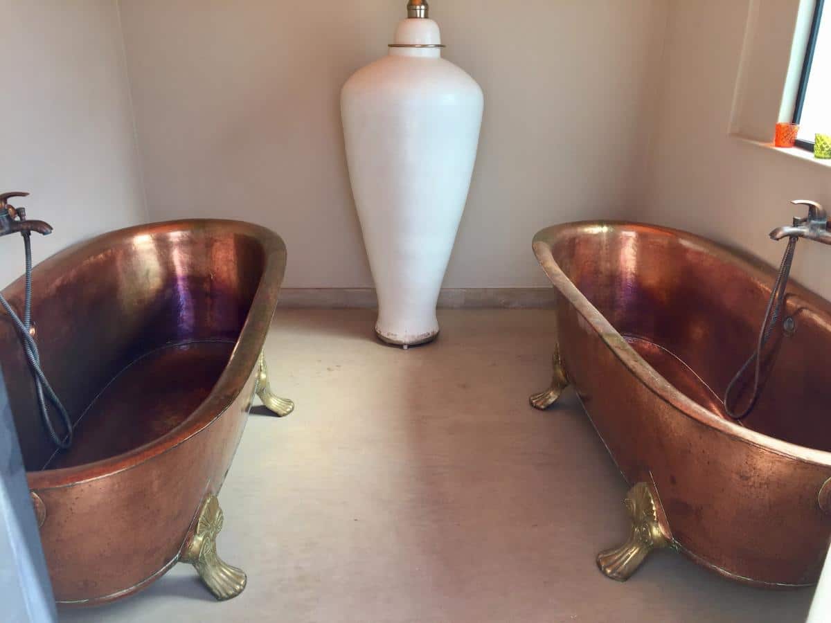 Zwei freistehende Kupferbadewannen mit Messingklauenfüßen und großer weißer Keramikvase im Les Bains D’Orient Marrakesch