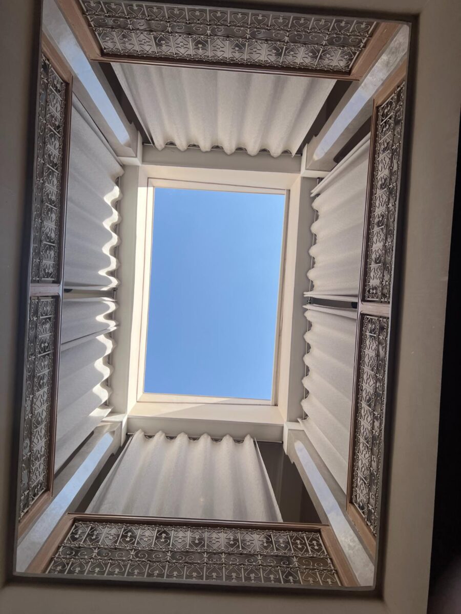 Blick nach oben durch das offene Innenhof-Oberlicht mit traditionellem marokkanischem Muschelputz und geschnitzten Details im Les Bains D’Orient