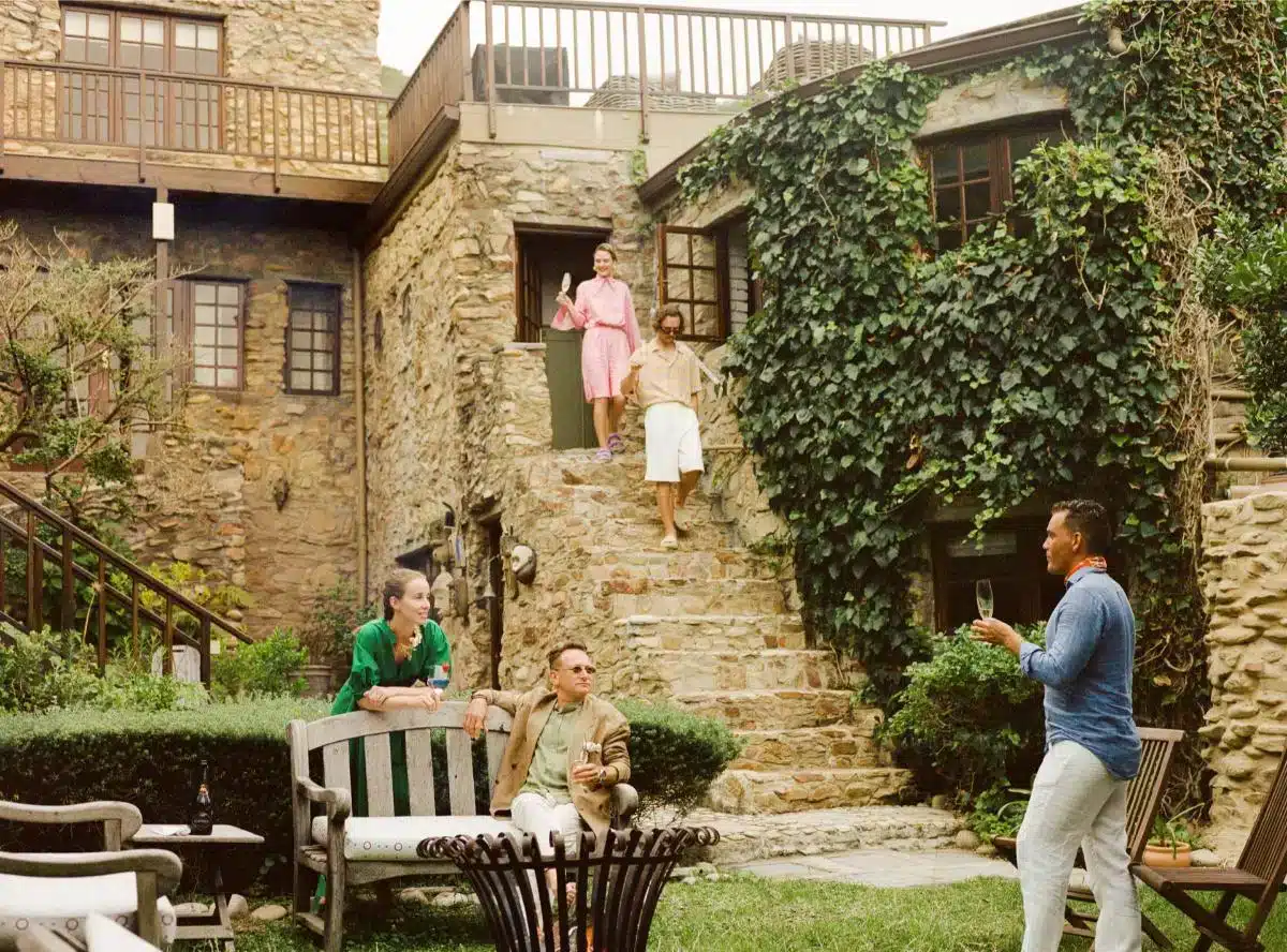 Guests relaxing in the garden of an ivy-covered stone villa booked through Insider Villas, with people on garden benches sharing drinks and conversation