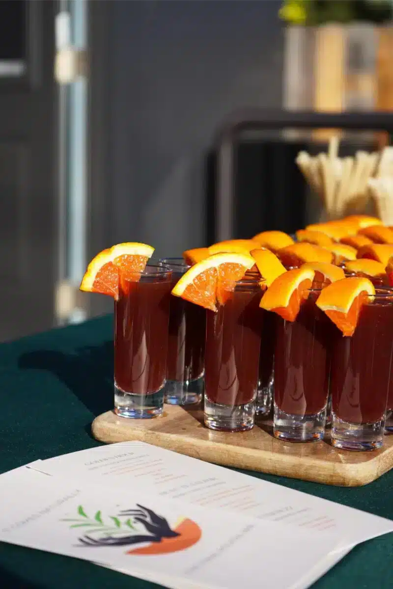 Funktionelle Wellness-Shots mit frischen Orangenscheiben auf einem Holzbrett bei The Healthy Hour