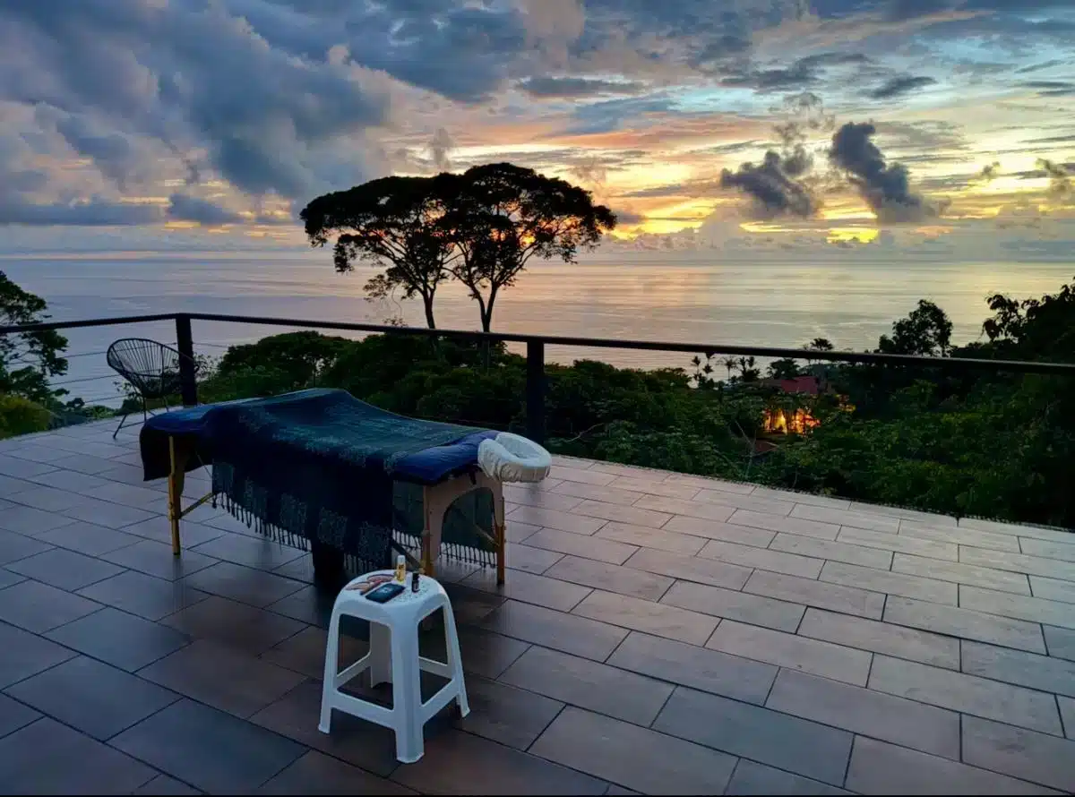 Outdoor massage table on a terrace overlooking the Pacific Ocean at sunset during Soul Alive Retreats Costa Rica