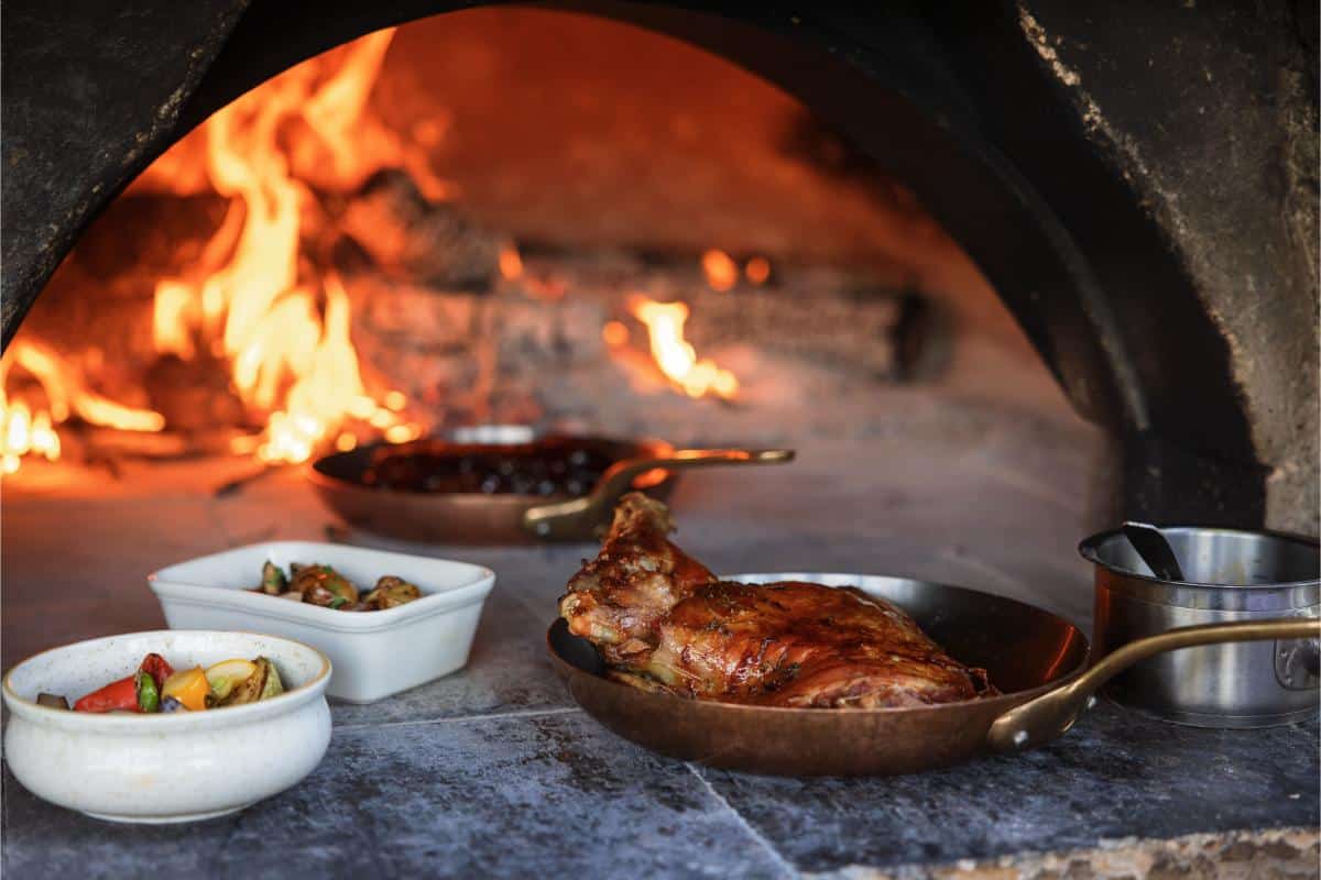 Close-up of food being cooked over open flames in a wood-fired oven at Lou Calen restaurant