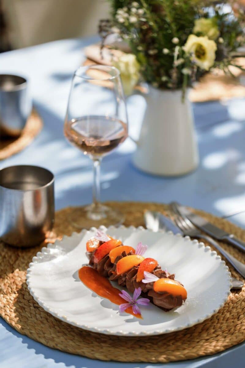 Glass of rosé wine being poured alongside an elegant gourmet dessert in the sunlight at Lou Calen