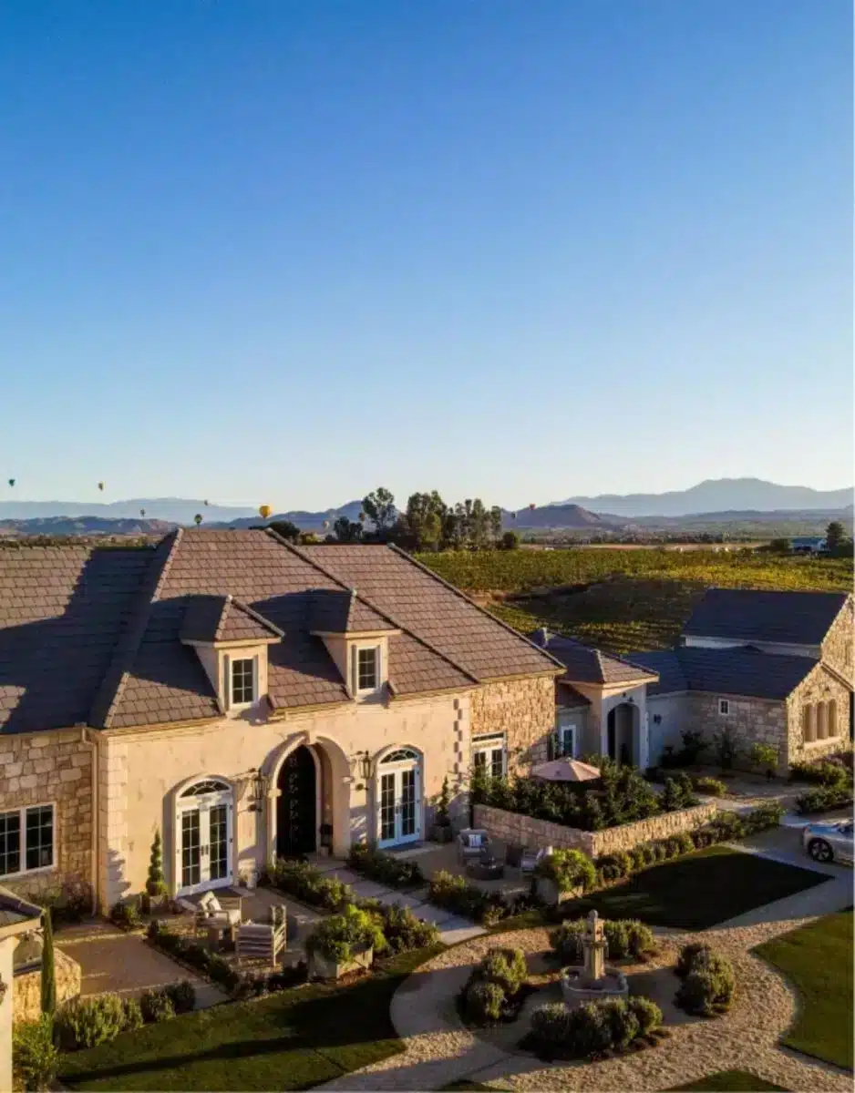Aerial view of Domaine Chardonnay estate in Temecula wine country showing the French-style main building, surrounding Chardonnay vineyards and mountain backdrop
