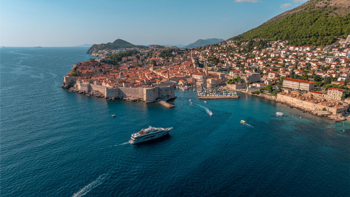 Aerial view of a historic Croatian coastal town with red rooftops and luxury yachts in the harbour