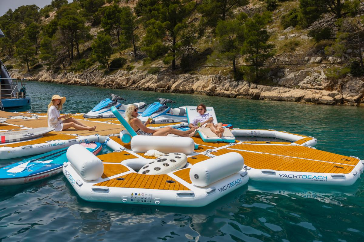 Guests relaxing on inflatable water toys next to a luxury yacht in turquoise Croatian waters