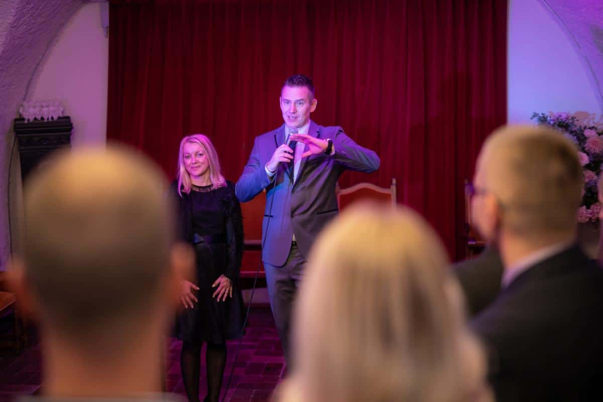 Mitja Mirtic presenting at a Goolets yacht charter event with red curtain backdrop and audience
