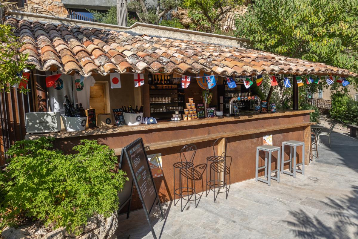 Grande Terrasse outdoor bar with festive bunting stone building and terracotta roof tiles at Lou Calen