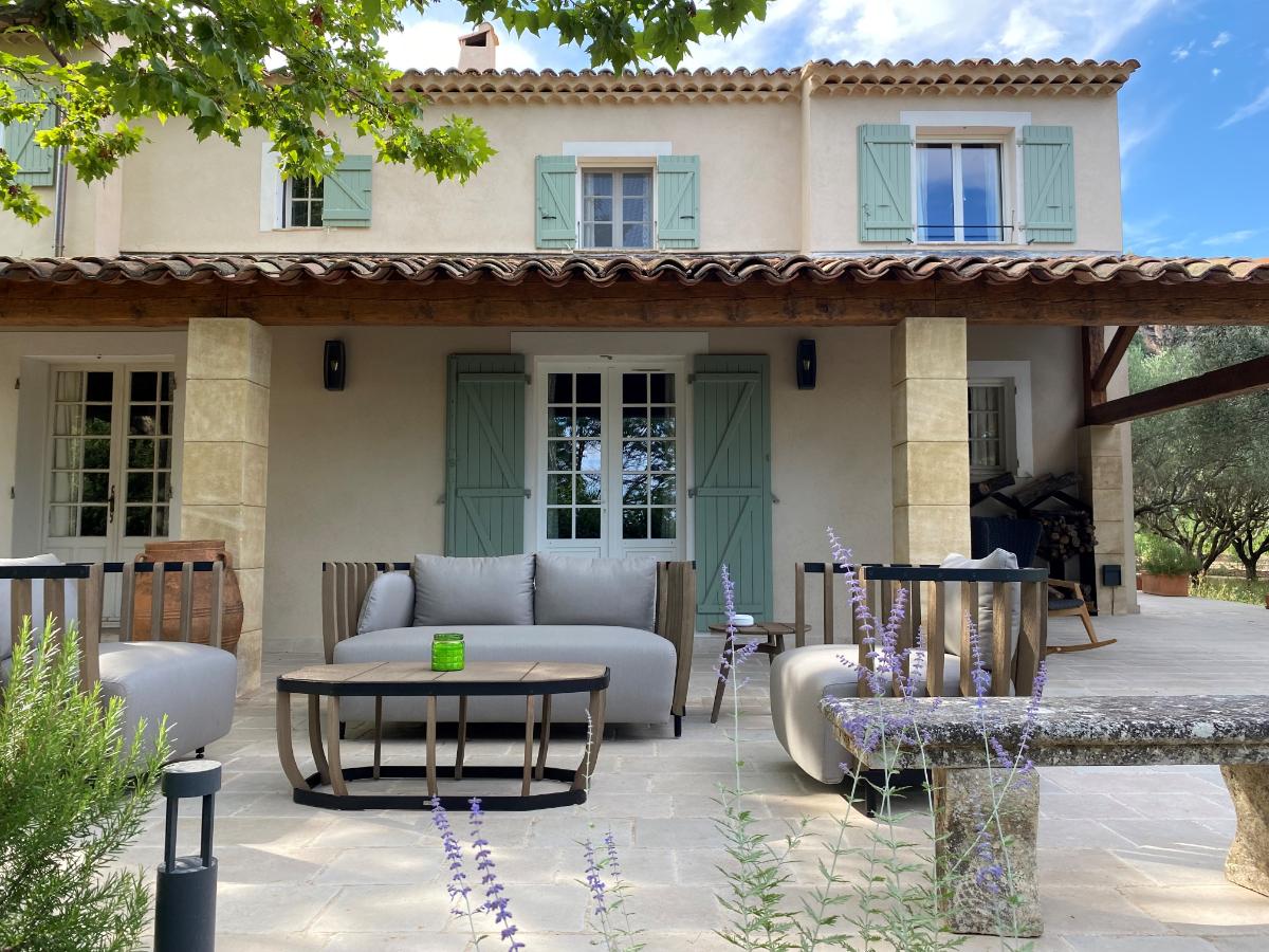 La Bastide Provençal building with green shutters stone terrace and modern outdoor sofa surrounded by lavender at Lou Calen
