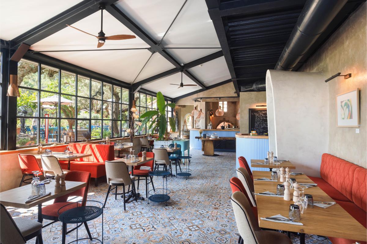 Le Bistrot covered terrace at Lou Calen with red accent chairs modern dining area and stone walls