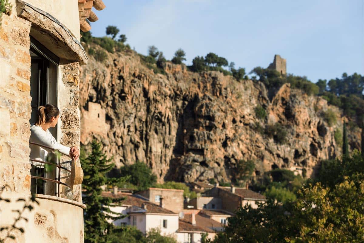The towering rock of Cotignac rising above the stone buildings and greenery of Lou Calen
