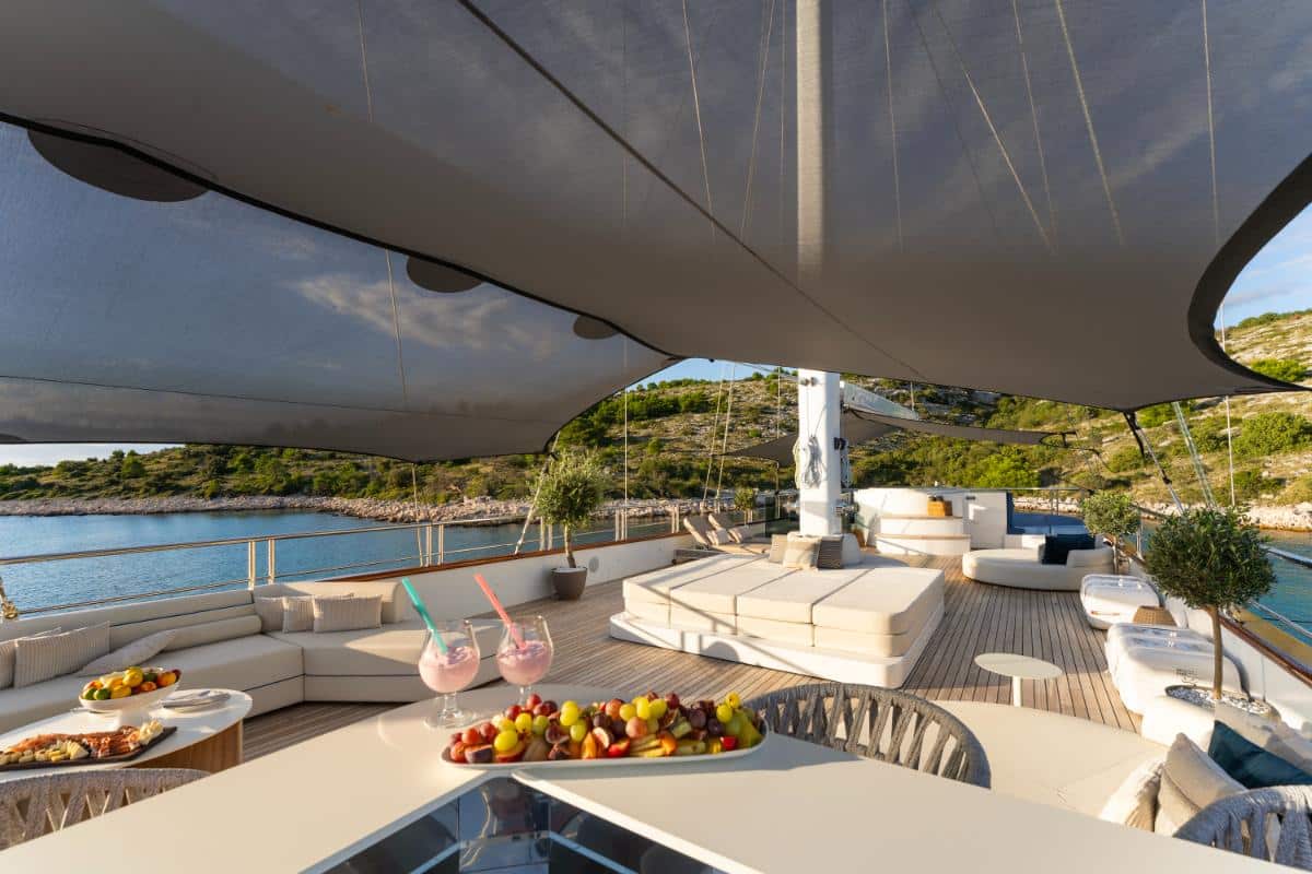 Sundeck of the Maxita luxury yacht with white cushions fruit platter and turquoise sea