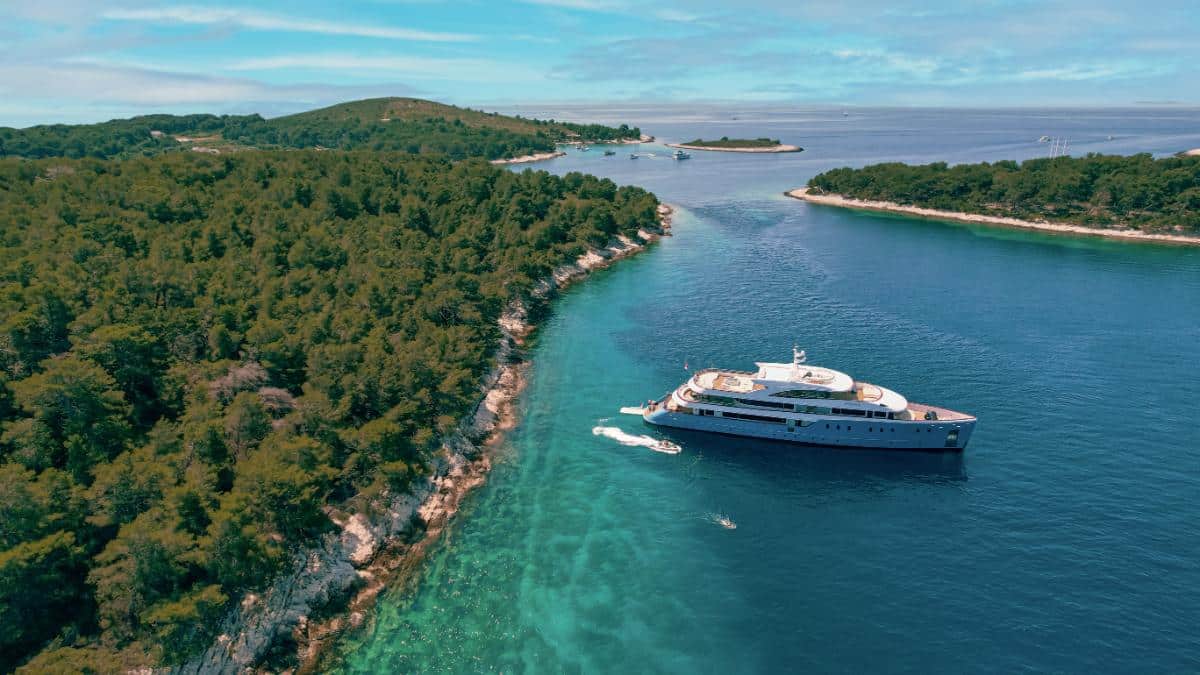 Aerial view of the Ohana luxury yacht anchored near a lush green Croatian island with turquoise water