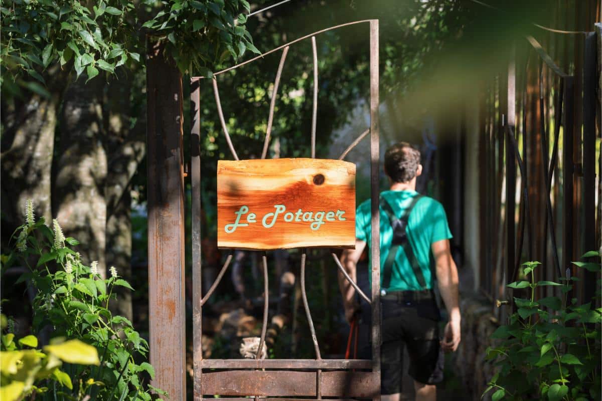 Le Potager vegetable garden entrance with a staff member walking among the greenery at Lou Calen