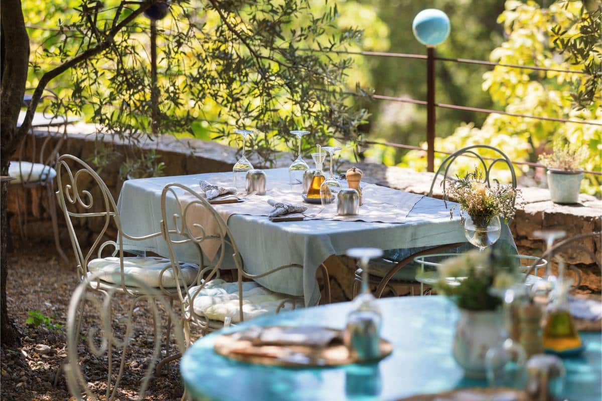 Secret Garden terrace at Lou Calen set for outdoor dining with white linens garden lamps and flowers