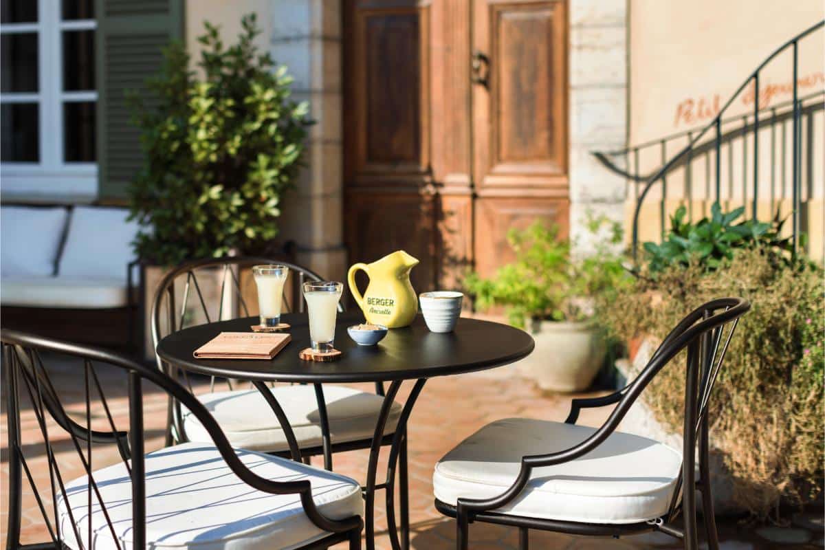 Outdoor bistro terrace with small round tables chairs and yellow pitcher at the pastis bar at Lou Calen