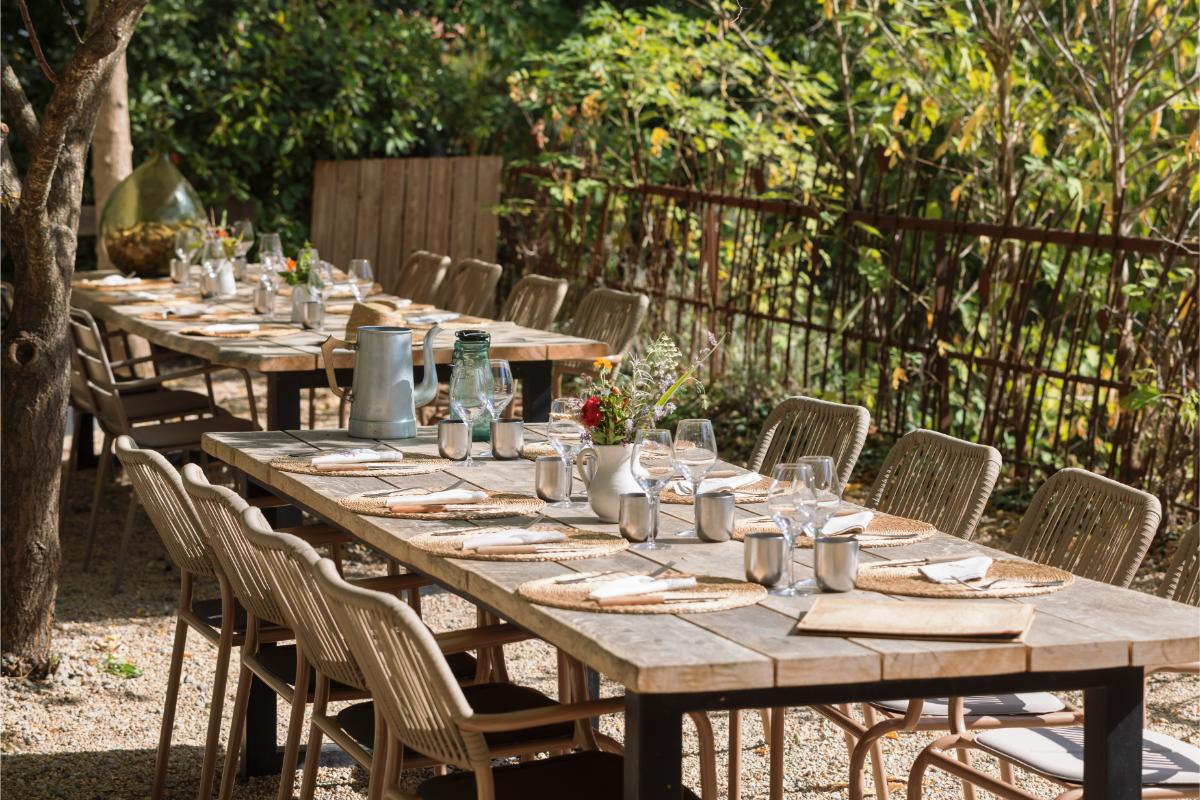 Long wooden dining table set for a group meal under a vine-covered pergola at Lou Calen