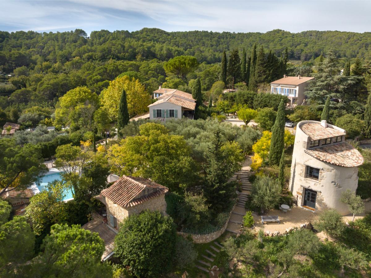 Elevated view of the Lou Calen estate with stone buildings pool and lush Provençal landscape in Cotignac