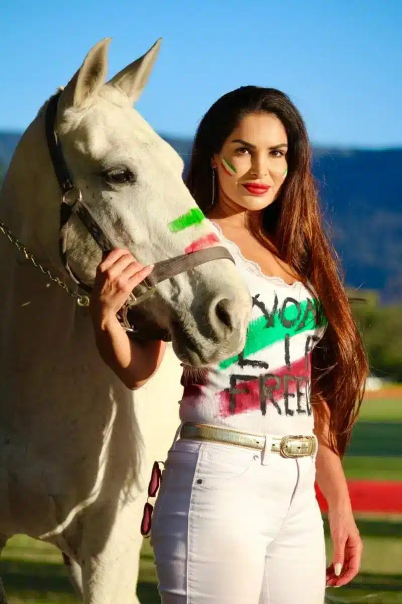 Sayé Yabandeh posing with a white horse wearing a painted t-shirt