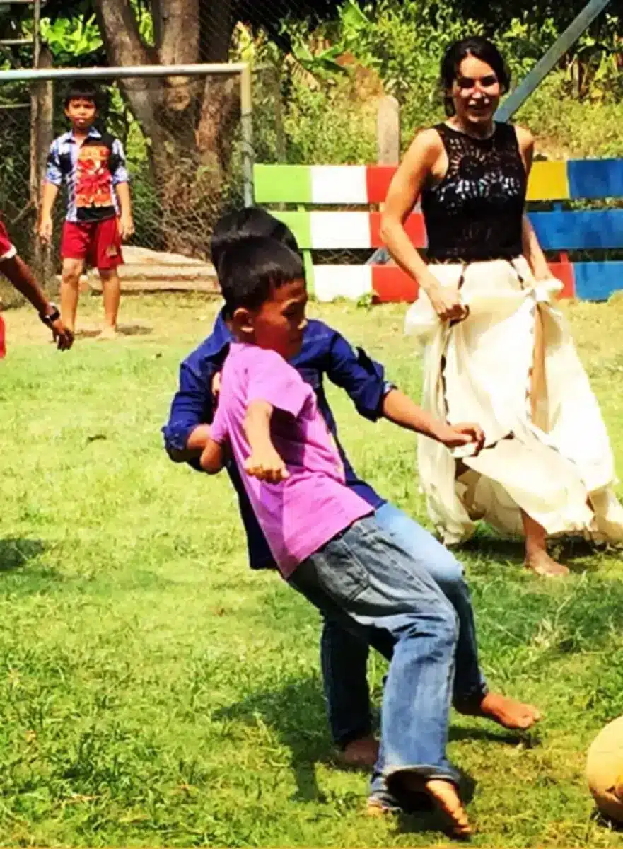 Children playing outdoors on grass during a Sacred Ascension Journeys community project in India