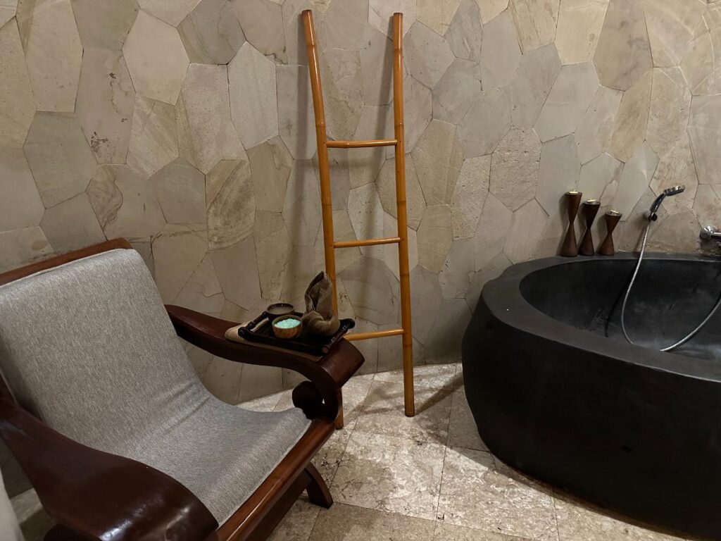 Spa massage treatment room at Munduk Moding Plantation Bali with padded treatment table and neutral stone-toned interior