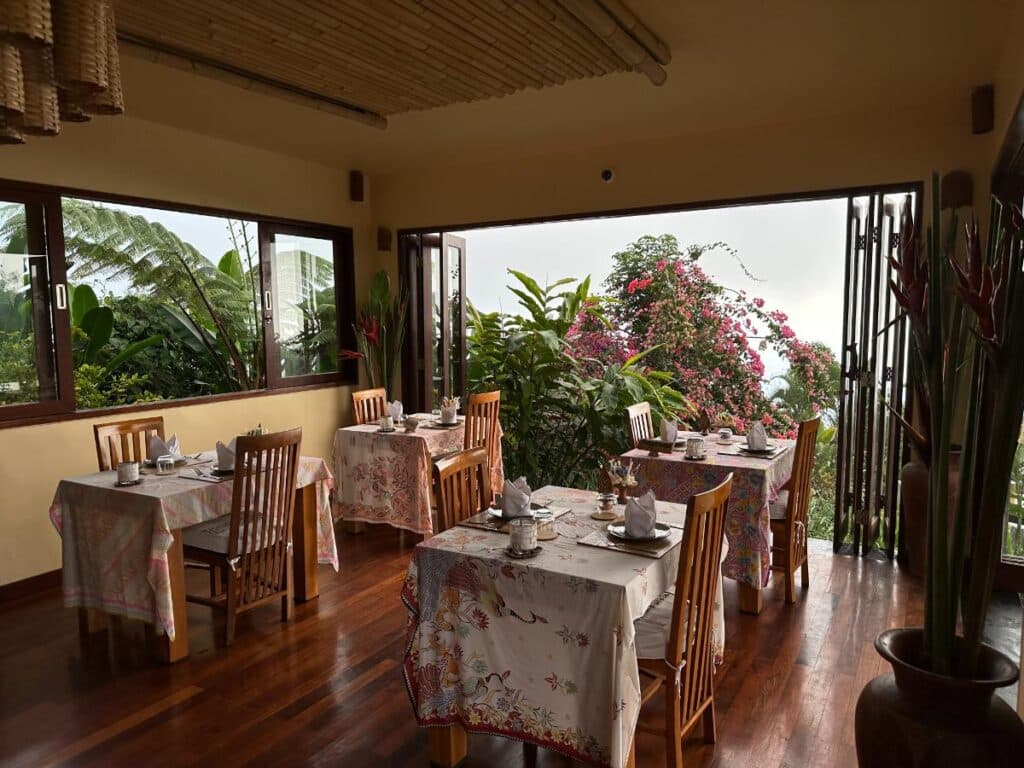 Breakfast dining area at Munduk Moding Plantation Bali restaurant with open-air garden view and colourful bougainvillea