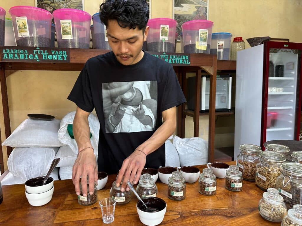 Barista preparing individual coffee cupping samples at Munduk Moding Plantation Bali tasting room with Arabica Honey variety packs