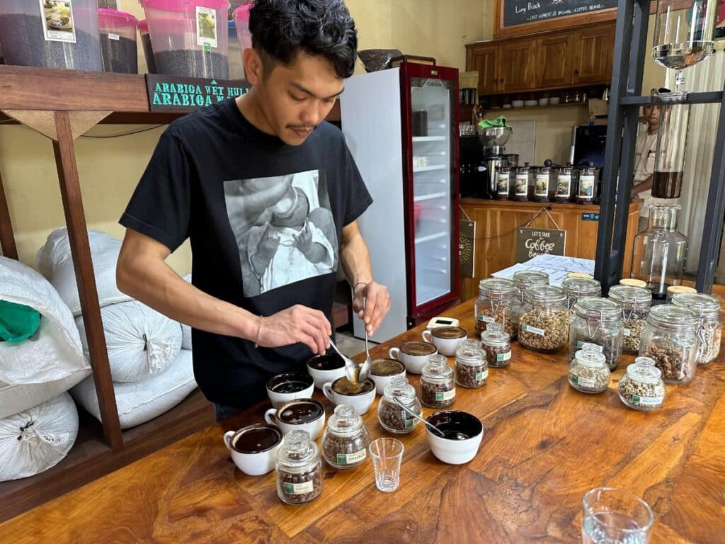 Barista conducting a coffee cupping session at Munduk Moding Plantation Bali pouring freshly brewed samples into bowls