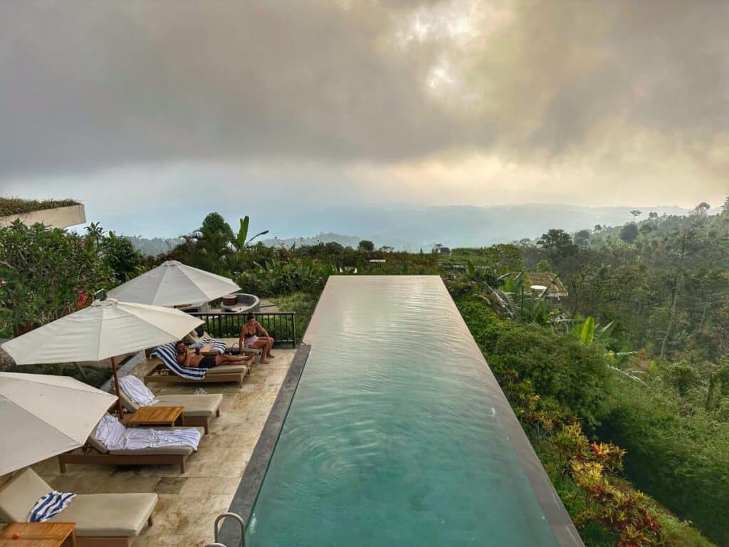Aerial view of Munduk Moding Plantation Bali's main infinity pool stretching toward the misty highland valley at dusk