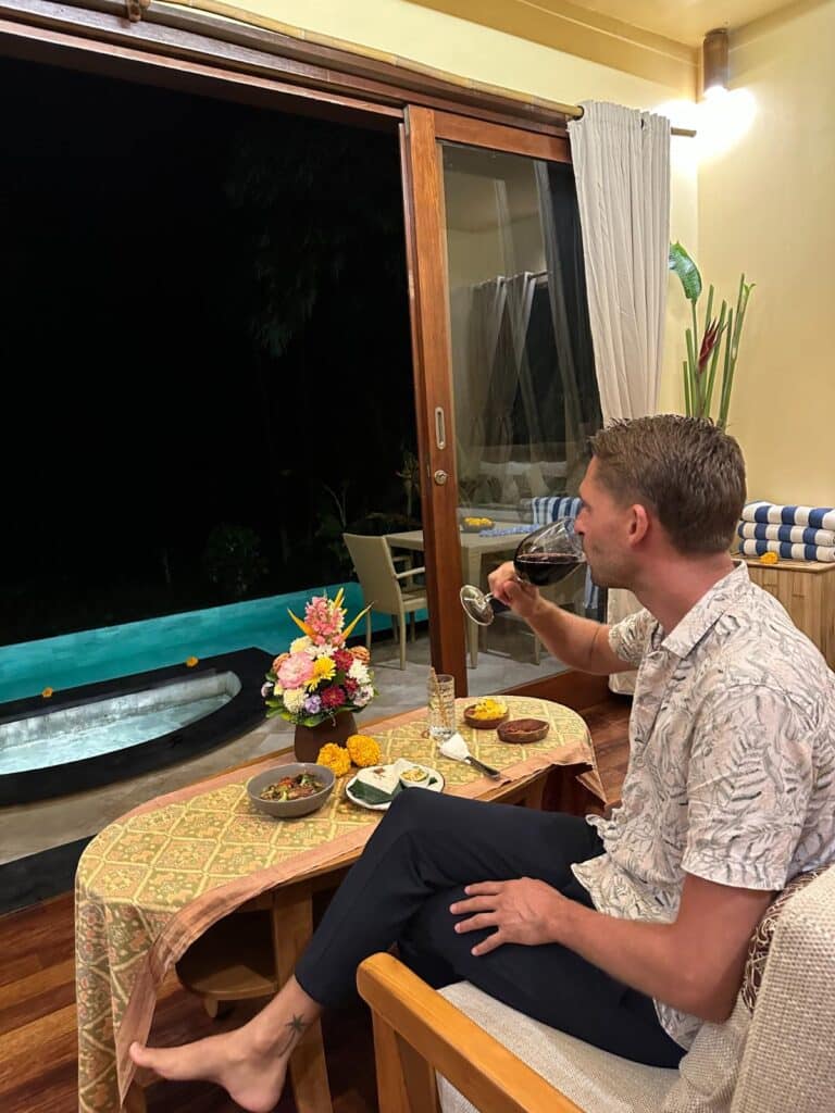 Relaxed evening scene at Munduk Moding Plantation Bali with guest having wine beside indoor-outdoor private pool room