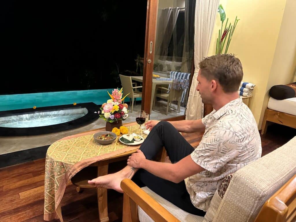 Guest sitting by private pool at Munduk Moding Plantation Bali in the evening enjoying wine and snacks by the water