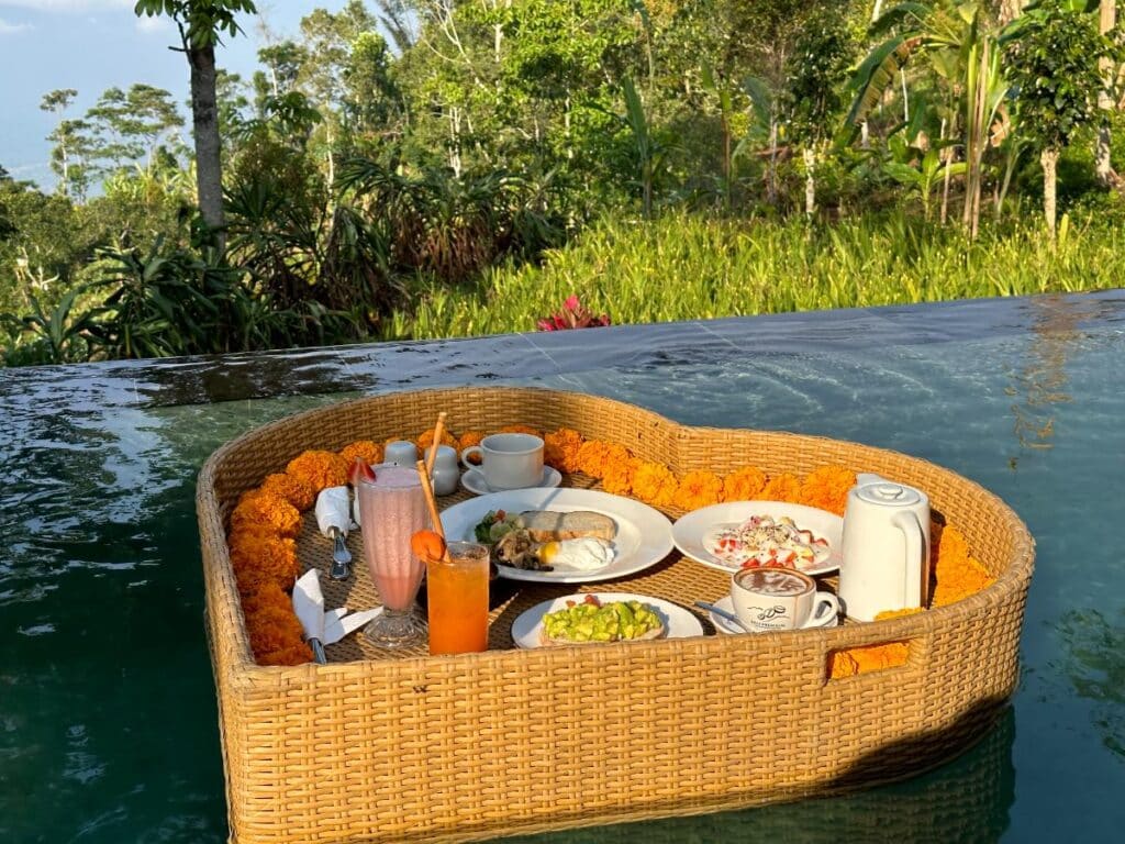 Heart-shaped wicker floating breakfast tray in villa pool at Munduk Moding Plantation Bali with Indonesian dishes and tropical fruit